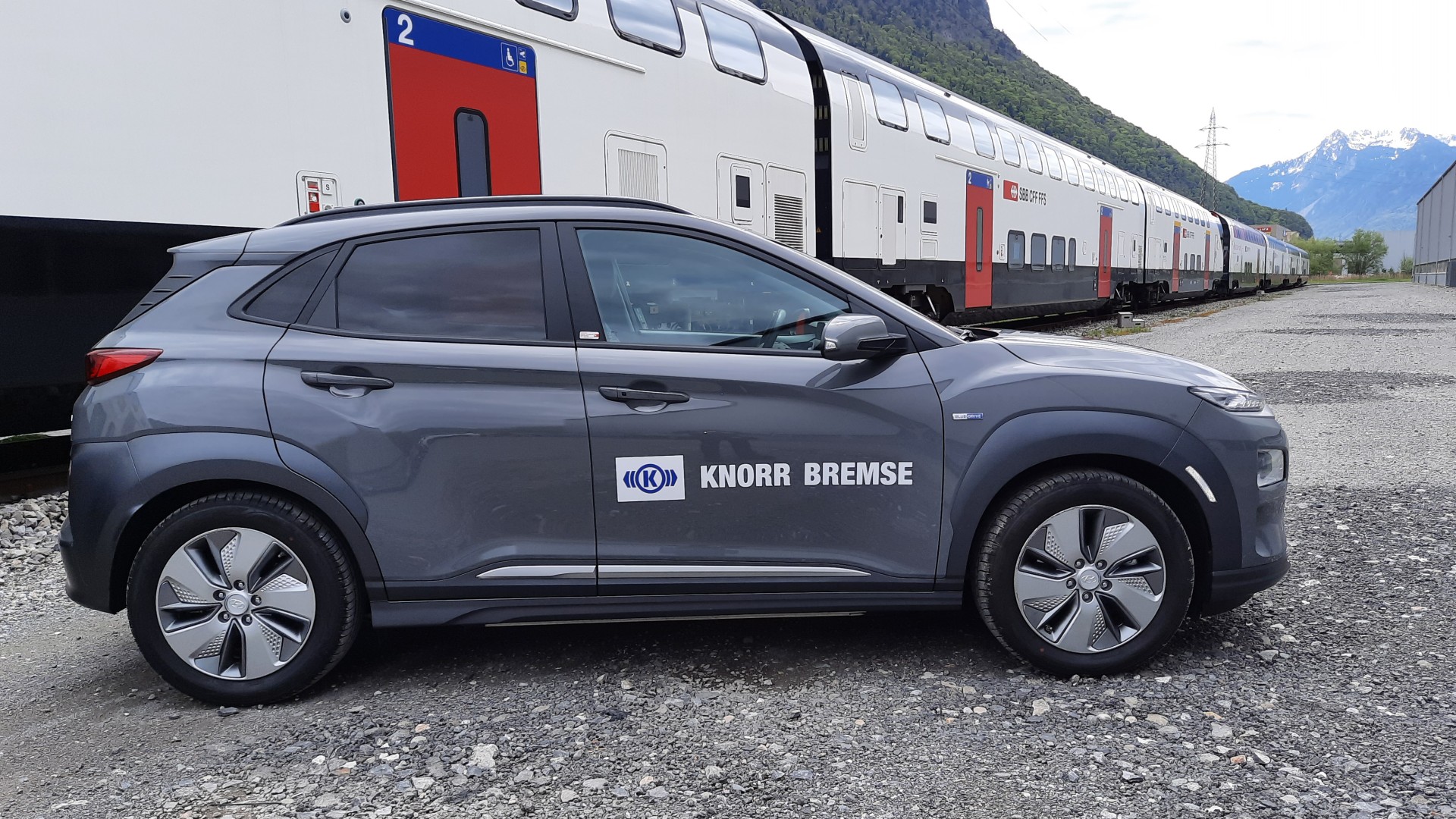 Knorr-Bremse Fahrzeug neben Zug auf Gleis.